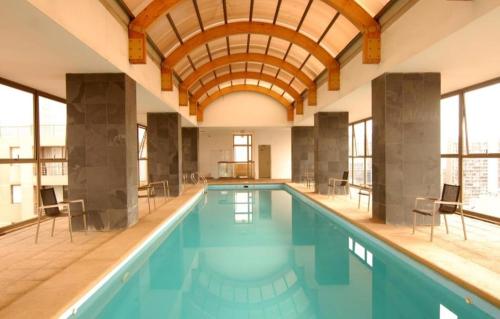 an indoor swimming pool with a wooden ceiling at Lubeck Suite Apartament in Santiago