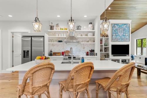 a kitchen with a white island with wicker chairs at Mountain-View Retreat with Hot Tub & Waterfalls in Cascade Locks
