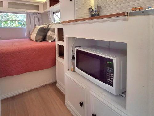 a small bedroom with a bed and a microwave at Vintage Coral Green in Nelly Bay