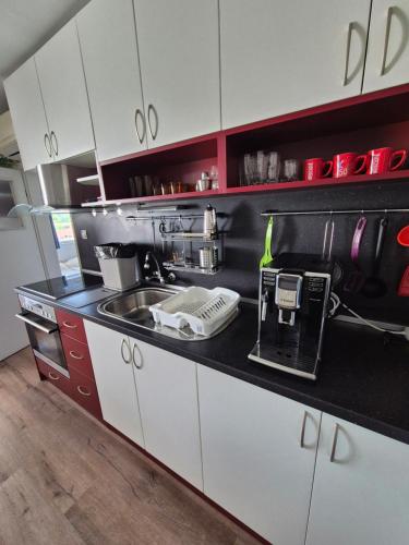 a kitchen with white cabinets and a sink at Апартамент за гости Роси in Sinemorets