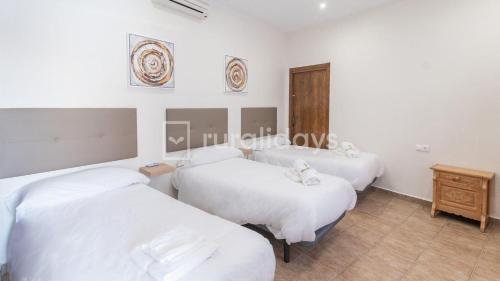 a room with three beds and a wooden table at Casa Rural Lucena in Lucena