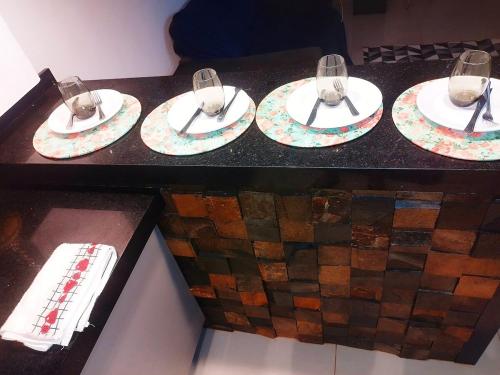 four plates with wine glasses on top of a counter at Casa 3 quartos com piscina próx ao Shopping in Tangara da Serra