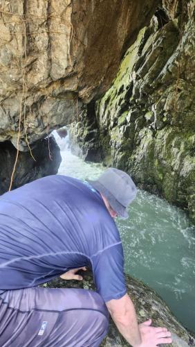 a man kneeling on a rock next to a river at Mi Verde Horizonte in Utuado