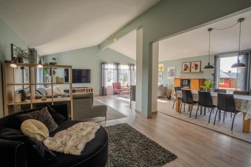 a living room with a couch and a dining room at Large modern house, perfect for northern lights hunting in Tromsø
