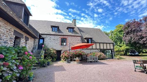 a house with a patio with a red umbrella at Sunset Family Guesthouse Mont Saint Michel in Céaux