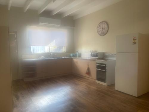 Il comprend une cuisine équipée d'un réfrigérateur et d'une horloge murale. dans l'établissement Broken Hill Desert Flower Cottage, à Broken Hill