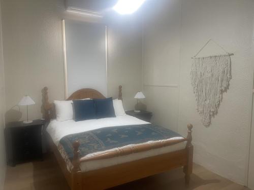 une chambre avec un lit avec des oreillers bleus et blancs dans l'établissement Broken Hill Desert Flower Cottage, à Broken Hill