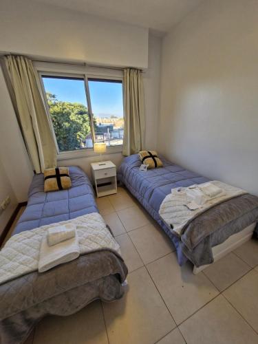 two beds in a room with a window at Consorcio 9 de Julio in San Juan