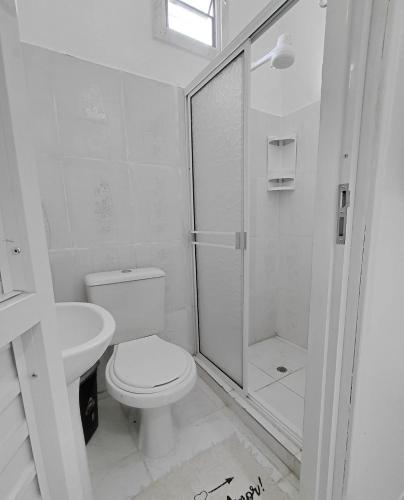 Un baño blanco con inodoro y ducha. en Seven Hotel, en Tabatinga