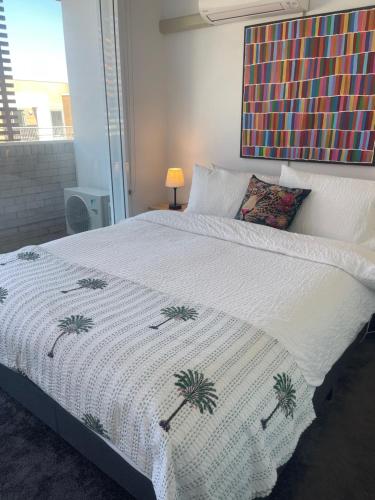 a bed with a white blanket with palm trees on it at Elegant Apartment, Heart of Newtown with Secure Parking in Sydney