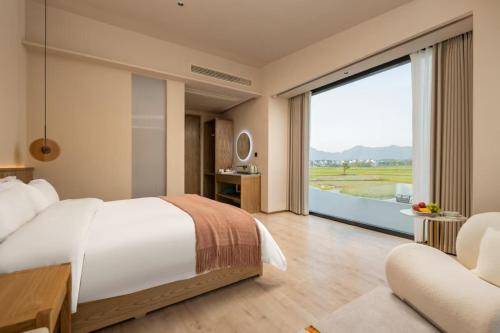 a bedroom with a large bed and a large window at Floral Hotel Jiuhuashan Xiluzhanyi B&B in Chizhou