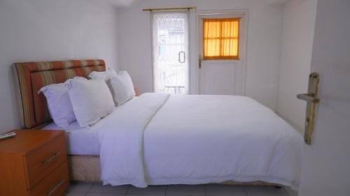 a bedroom with a white bed and a cross on the door at Villa Dalia Puncak H1-26 in Cikundul