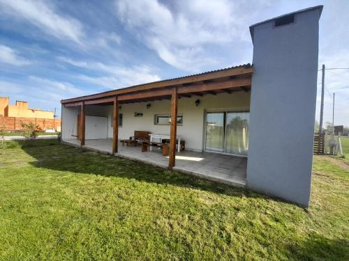 a house with a large porch with a picnic table at Casa en Chapadmalal con Piscina in Mar del Plata
