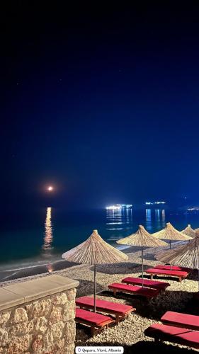 a row of umbrellas on a beach at night at Sevilia Rooms in Qeparo