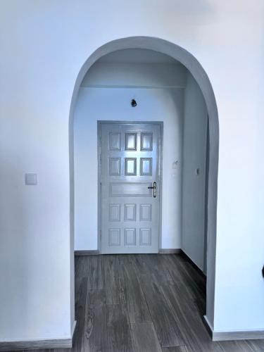an arched hallway with a white door and wooden floors at Sevilia Rooms in Qeparo