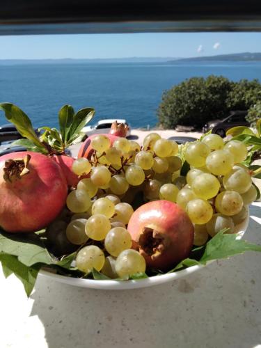 a bowl of fruit with apples and pomegranates at Apartment Hortenzija in Baška Voda