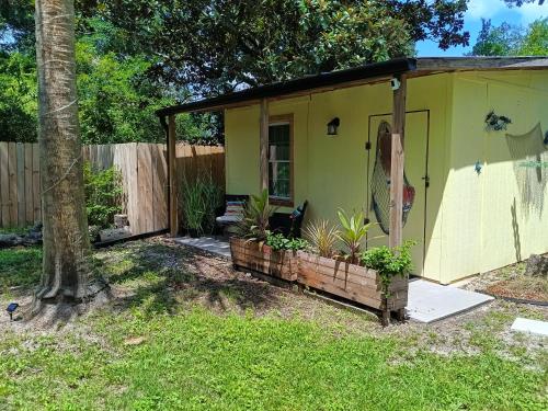 a small yellow house with plants in a yard at Pensacola hidden gem cottage 3 minutes from Navy Base, pet friendly in Pensacola