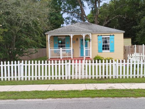 a small house behind a white picket fence at Pensacola hidden gem cottage 3 minutes from Navy Base, pet friendly in Pensacola