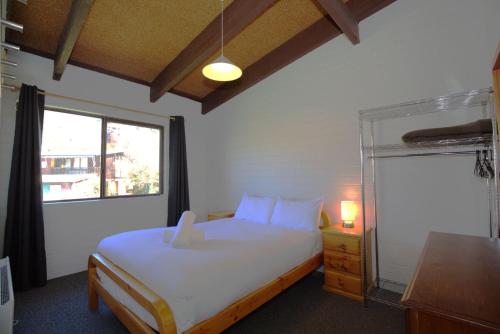 a bedroom with a white bed and a window at Alpha Centauri - 8 - 39 Gippsland Street in Jindabyne