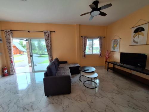 a living room with a couch and a ceiling fan at บ้านน้ำผึ้งโฮมสเตย์ in Suan Phung