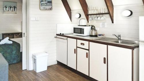 Una cocina con gabinetes blancos y un fregadero. en Picnic Bay Chalet Unit 2, en Picnic Bay
