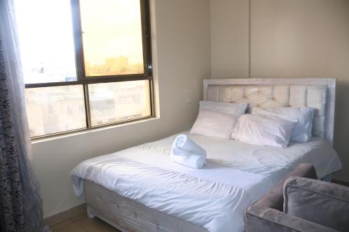 a bedroom with a bed with white sheets and pillows at Maya City View Studios in Nairobi