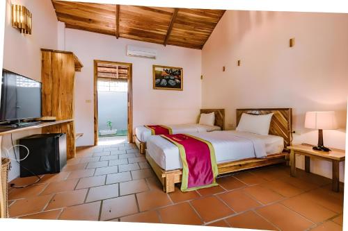 a bedroom with two beds and a flat screen tv at StarHill Resort Phú Quốc in Phu Quoc