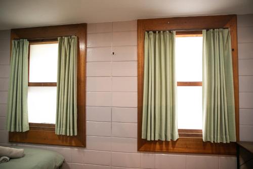 a bedroom with two windows with green curtains at 香琉 Kaoru in Miyako Island