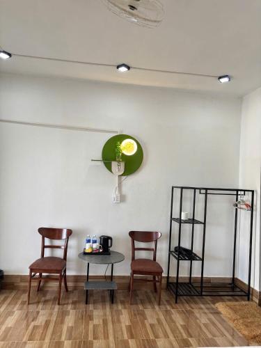 a room with three chairs and a table and a clock at Horizon Homestay in Phong Nha