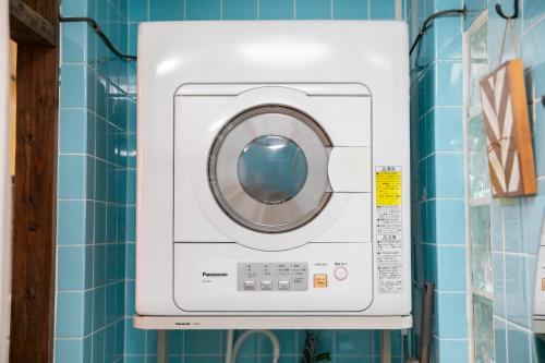 a washing machine in a bathroom with blue tiles at 香琉 Kaoru in Miyako Island