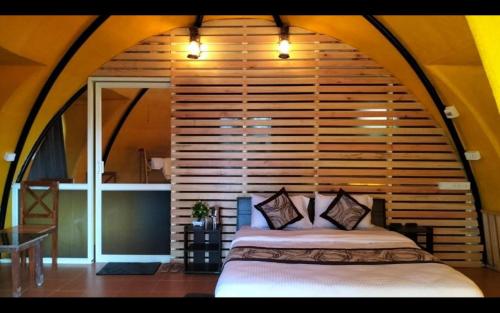 a bed in a room with a wooden wall at Kathadia Homestay in Cherambane