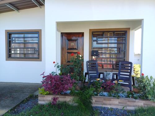 a house with two chairs and a table and flowers at Casa via Boquete in Alto Boquete