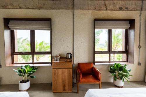 a bedroom with two beds and a chair and two windows at WoCAL Resort Ke Ga in Xóm Chum Găng