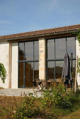 ein Haus mit großen Glasfenstern und einem Regenschirm in der Unterkunft Restored Farm Near La Rochelle in La-Gripperie-Saint-Symphorien
