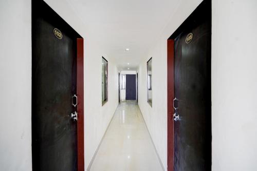 斋浦尔HOTEL O HOLIDAYS INN的走廊设有黑色门和白色墙壁