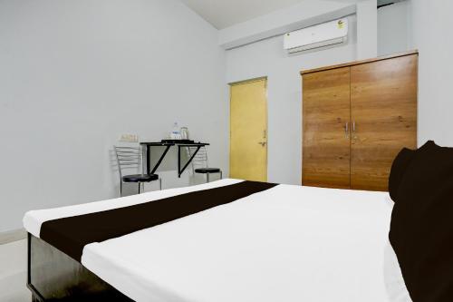 a bedroom with a white bed and a wooden cabinet at Hotel O Happy Inn in Raipur