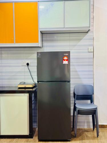 a refrigerator in an office with a chair and a desk at Best Day Homestay ! in Kangar