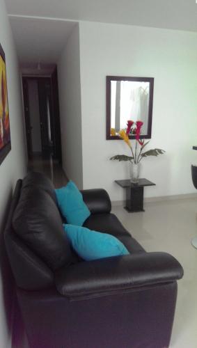 a black leather couch in a living room with blue pillows at Palmagua in Barranquilla