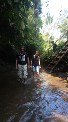 two men walking through a stream in the jungle at Tetebatu Indah Homestay in Tetebatu
