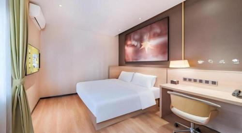 a hotel room with a white bed and a desk at IU Hotel Kunming Jinma Bijifang Joy City in Kunming