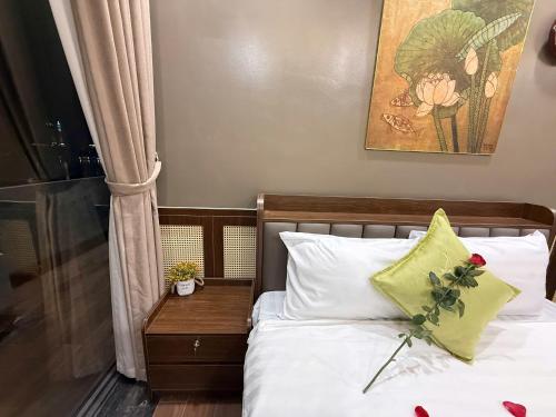 a bedroom with a bed with white sheets and green pillows at MD Hotel in Mỹ Lộc