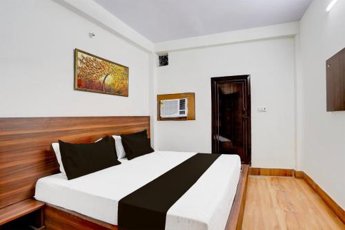 a bedroom with a bed with white and black sheets at Hotel O Mayur Deluxe in New Delhi