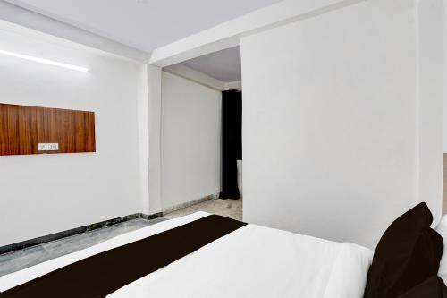 a bedroom with a white bed and a wooden door at Hotel O Mayur Deluxe in New Delhi