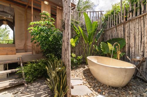 a bath tub sitting in a garden next to a fence at WoCAL Resort Ke Ga in Xóm Chum Găng