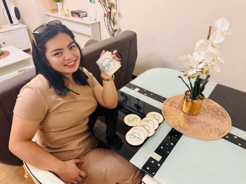 a woman sitting at a desk holding a mug at Angsana Breeze at Paseo Verde Las Piñas in Manila
