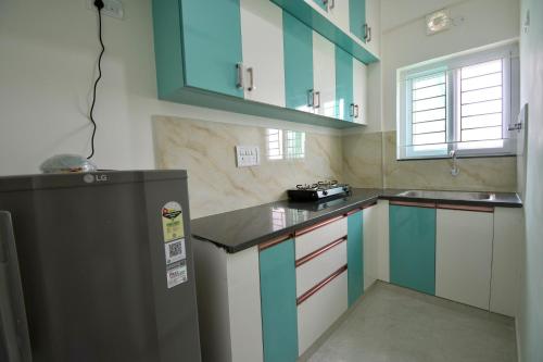 a kitchen with blue and white cabinets and a refrigerator at HomeSlice Manor, Premium Apartment in Whitefield in Bengaluru