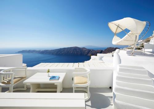 a table and chairs on the side of a white building at White Santorini in Imerovigli