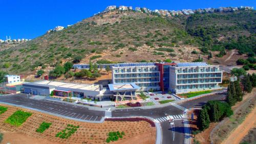 an aerial view of a building with a hill in the background at HI - Haifa Hostel in Haifa