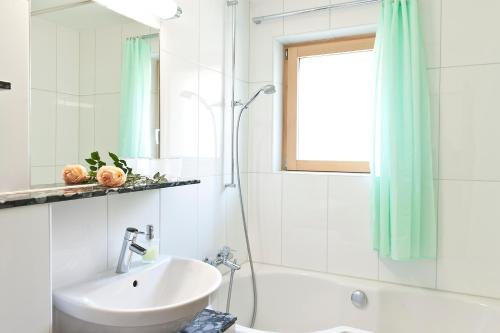 a white bathroom with a sink and a shower at Pollux Family Apartment in Zermatt
