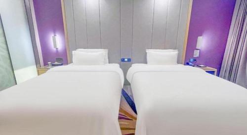 two beds in a room with purple walls at Lavande Hotel Huizhou Shiwan in Huizhou